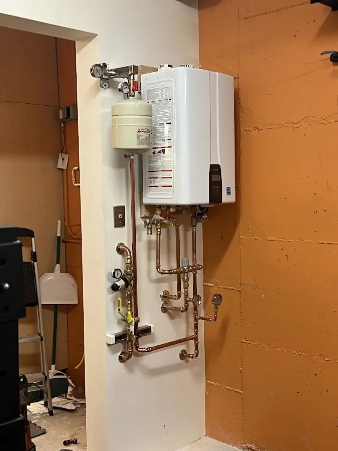 Plumbing technician inspecting water heater connections in Edgerton